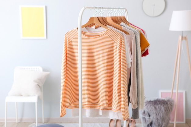 Fashionable clothes on a rack in the interior of a bright room