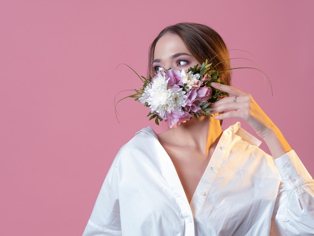 Fashionable concept face mask fresh and lively floral fragrance portrait in the studio on a pink bac...