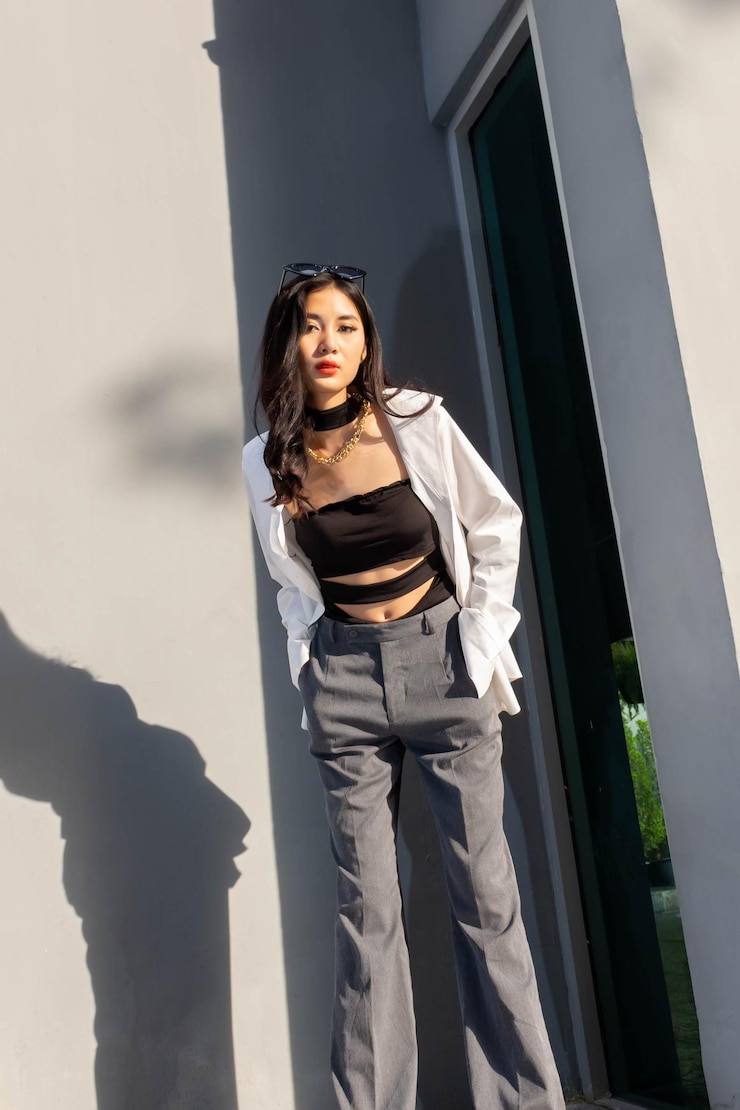 Photo 흰색 셔츠와 회색 벽 근처 포즈와 회색 바지에 유행 개념 패션 여자