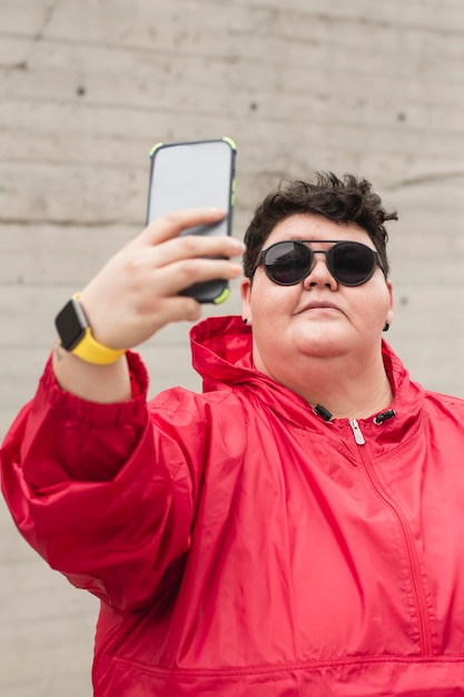 Foto donna formosa alla moda che si fa un selfie per strada