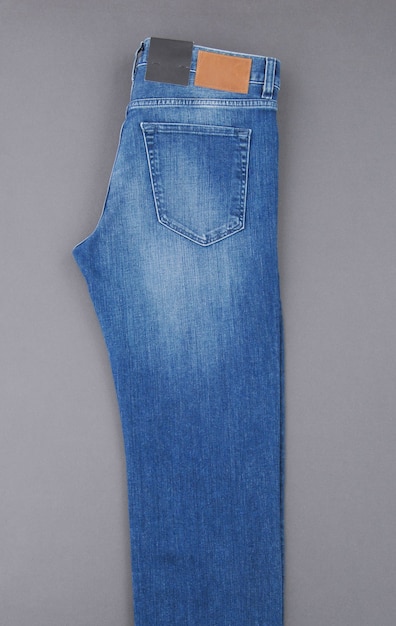 Fashionable denim pants on grey background, top view