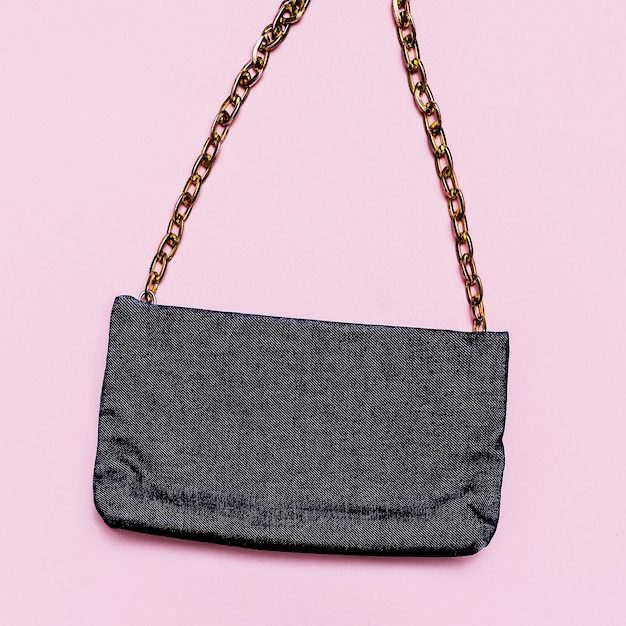 Fashionable female denim clutch on pink background