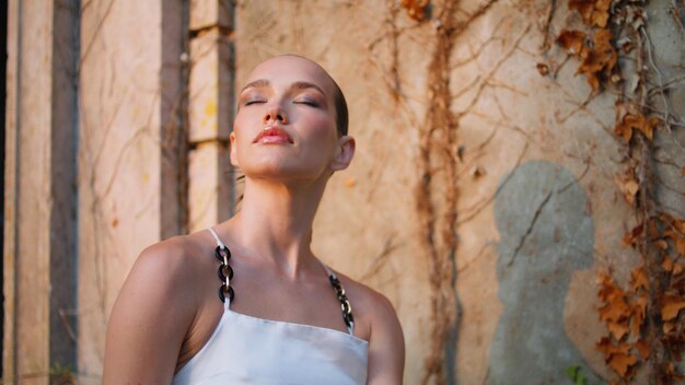 Fashionable girl closing eyes enjoying soft evening sunlight outdoors close up