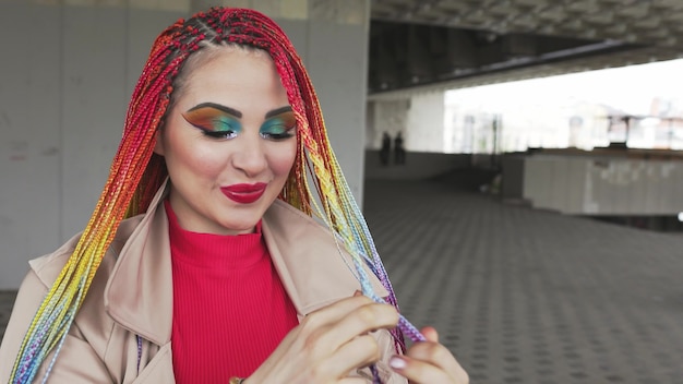 Fashionable girl in a jacket straightens her colored african braids