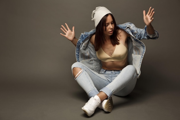 Fashionable girl in jeans and a bra isolated on a gray background