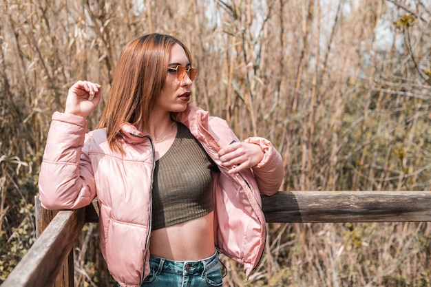 Fashionable girl leaning on a wood fence