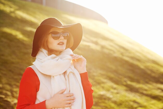 秋の公園でポーズをとる帽子とサングラスを身に着けているファッショナブルな女の子。テキスト用のスペース