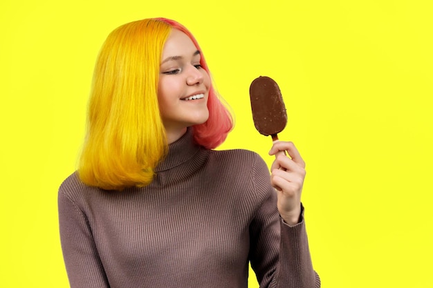 Fashionable girl with chocolate ice cream on stick on yellow background