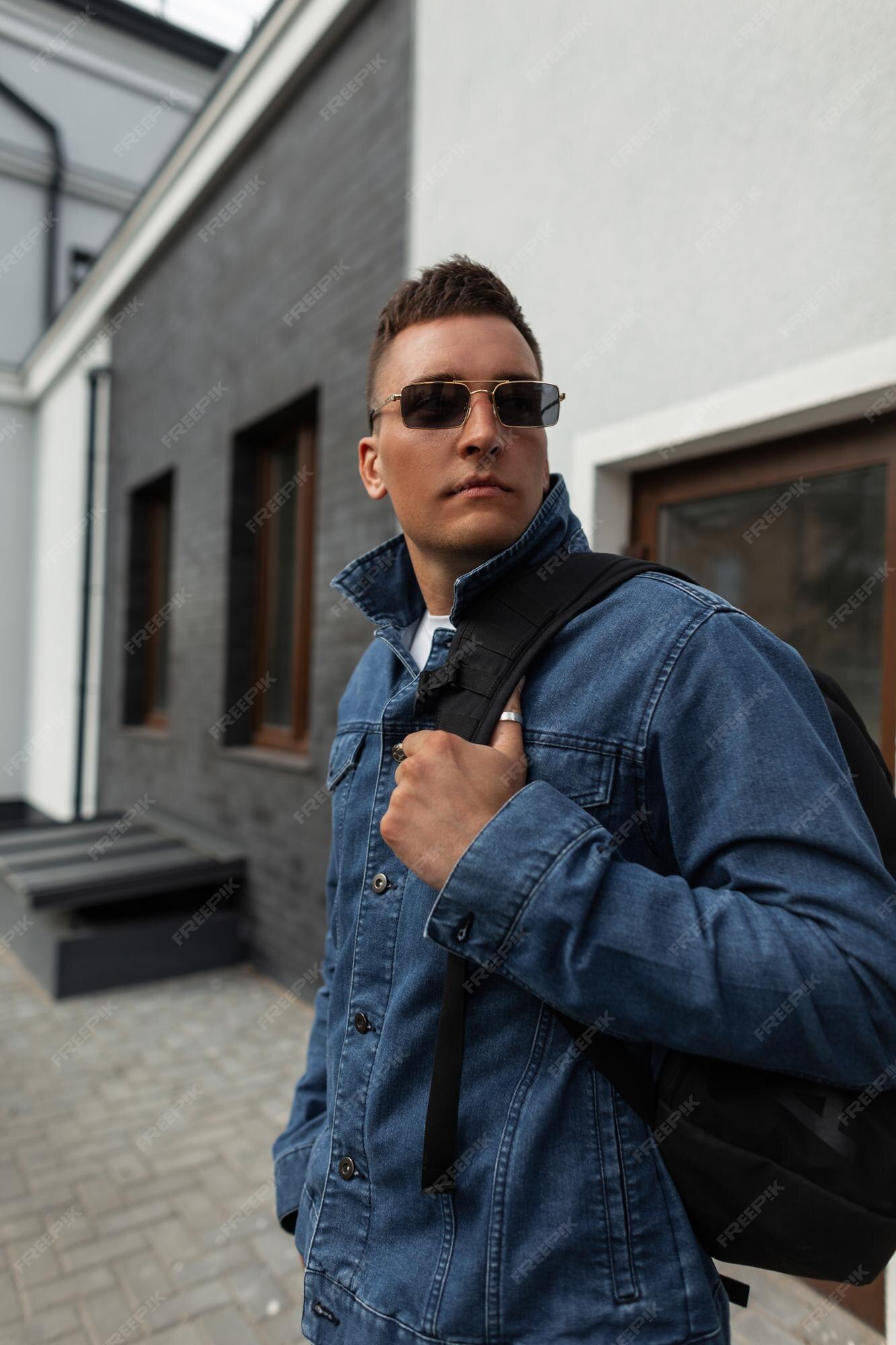 Premium Photo | Fashionable handsome brutal man model with glasses and hair in a fashion blue jeans jacket with a backpack walking in the city Premium Photo | Fashionable handsome brutal man model with glasses and hair in a fashion blue jeans jacket with a backpack walking in the city