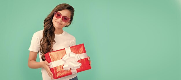 Fashionable happy kid in sunglasses hold gift box birthday Kid girl with gift horizontal poster Banner header with copy space