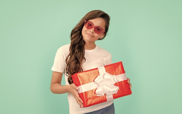 Foto il bambino felice alla moda in occhiali da sole tiene il compleanno della confezione regalo