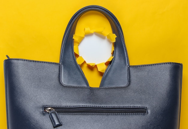 写真 引き裂かれた穴と黄色の背景にファッショナブルな革のバッグ。上面図