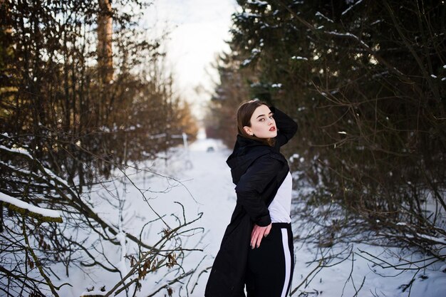 Fashionable long legs brunette model in long black cloak posed outdoor at winter day