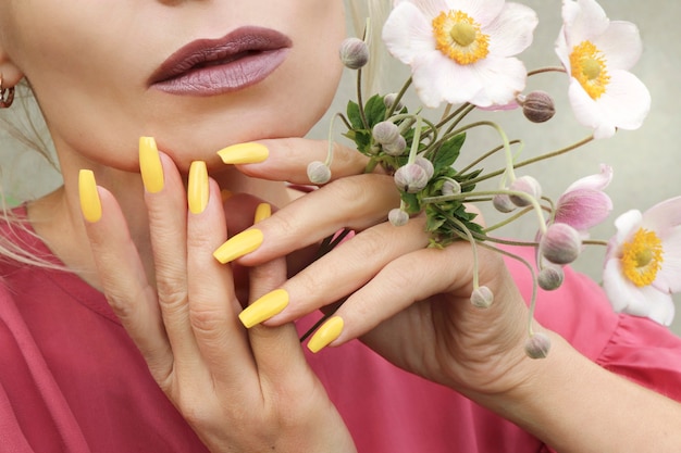 Fashionable makeup and yellow manicure on long shaped nails