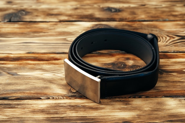 Fashionable male belt on brown wooden background close up