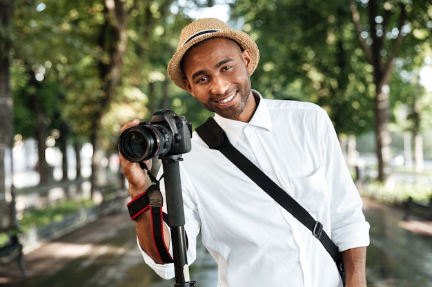 Uomo alla moda nel parco con il cappello che fa fotografie