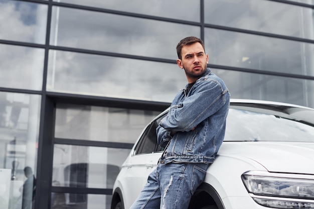 Fashionable man standing near car outdoors against modern business building