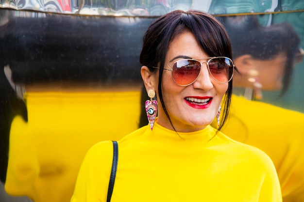 Fashionable mature woman wearing yellow top and sunglasses in city