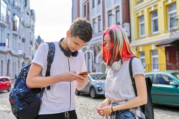 Fashionable modern youth lifestyle technology urban style\
couple of trending teenagers friends with smartphone on city\
street