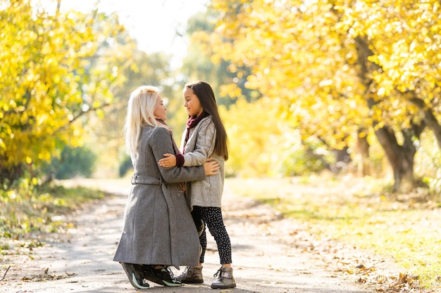 Fashionable mother with daughter. Family in a autumn park. Little daughter in a coat.