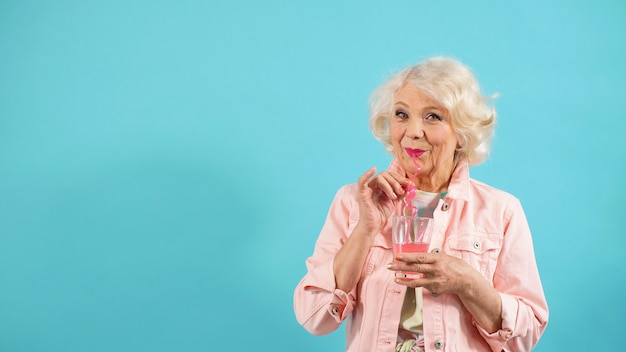 fashionable pensioner poses  with a cocktail in her hand