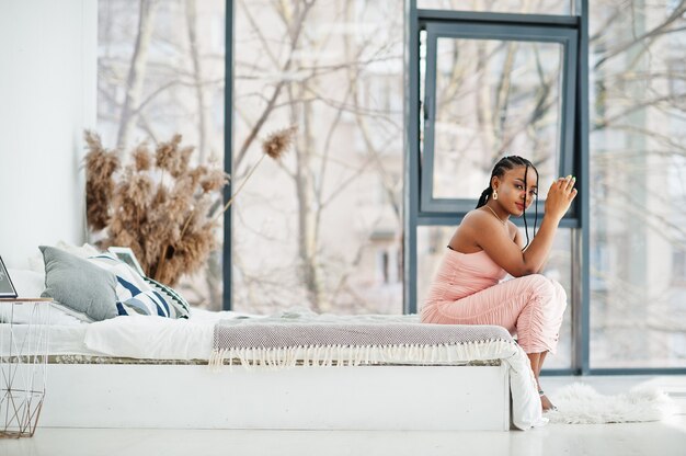 Fashionable photo of young beautiful romantic african american woman sitting on the bed