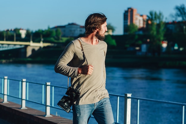 Fashionable photographer walking around the city with a retro photo camera