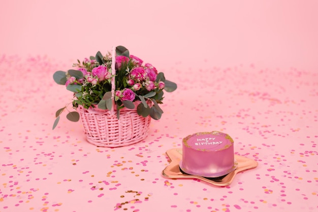 Fashionable pink and gold festive Korean bento cake on a golden plate in the shape of a star on a pink background with confetti and a basket with fuchsia roses