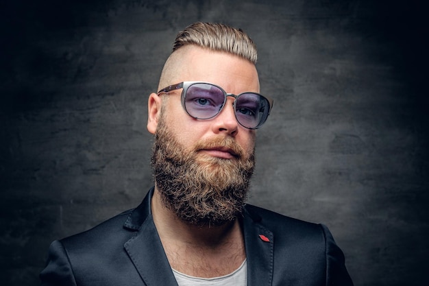 Fashionable portrait of bearded male in purple sunglasses isolated on grey vignette background.