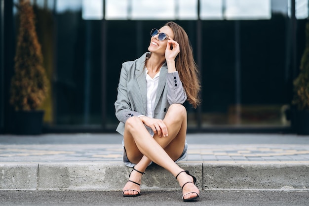 街の通りに座っているファッショナブルなきれいな女性