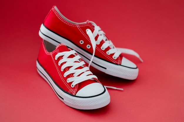 Fashionable red sneakers with white laces on red background