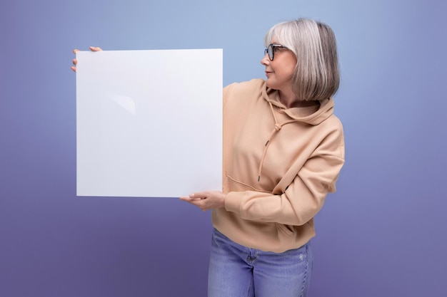 Fashionable s business woman with grayhaired with poster mockup on studio background with copy space