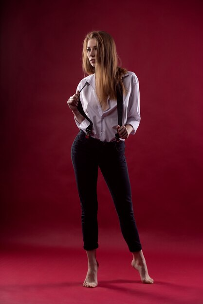 Fashionable sexy young woman posing in an unbuttoned shirt on a red background