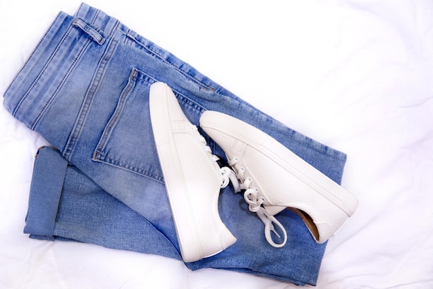 Fashionable sneakers and jeans on textile background