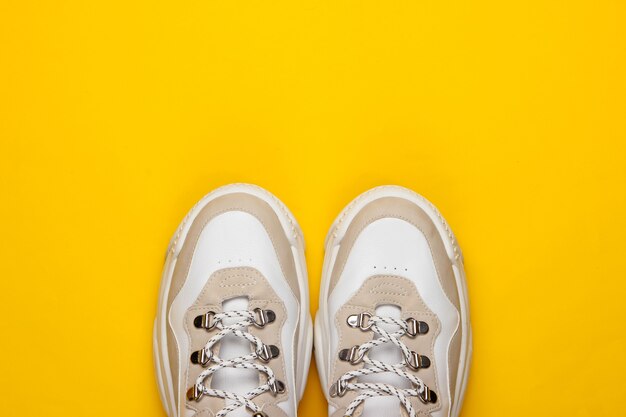 Fashionable sneakers on yellow