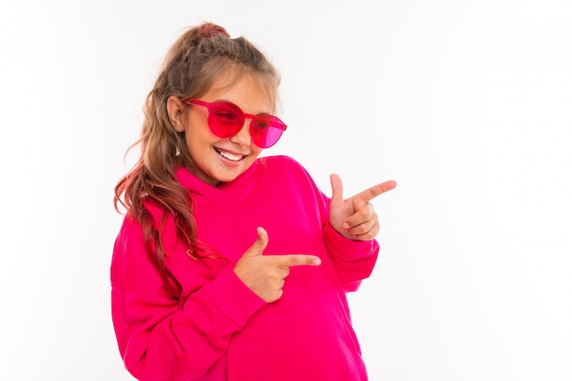 Fashionable teenager girl in pink hoody and with pink sunglasses gesticulates