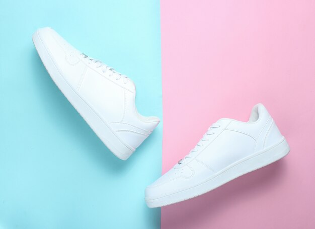 Fashionable white sneakers on a colored pastel table, minimalism, top view, creative layout, step
