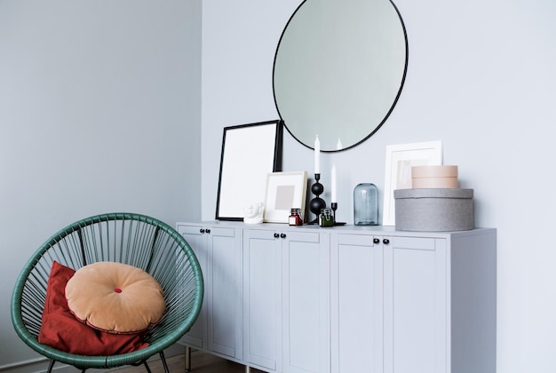 Fashionable wicker chair, a console with decor items and a
mirror against a gray wall in the interior of the room