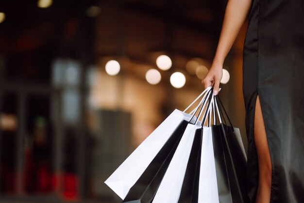 Foto donna alla moda vestita di un abito nero con borse della spesa.