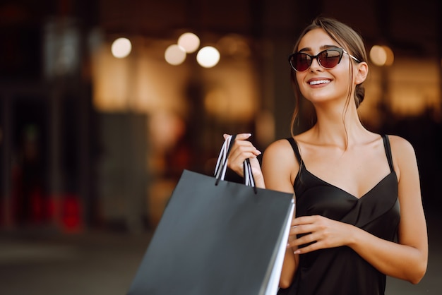 Fashionable woman dressed in a black dress with shopping bags.