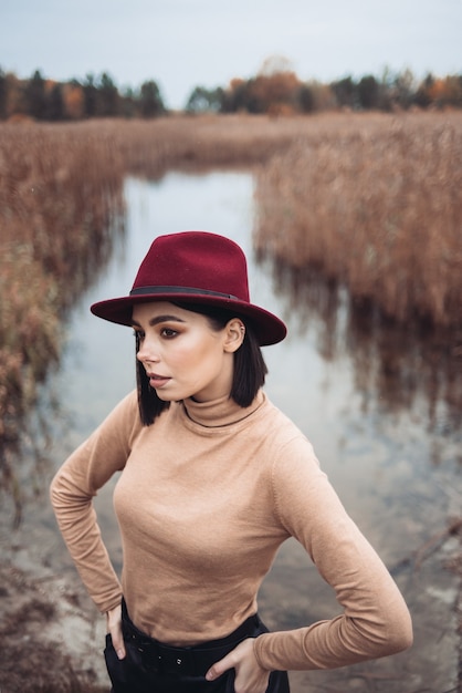Fashionable woman near the lake in hat