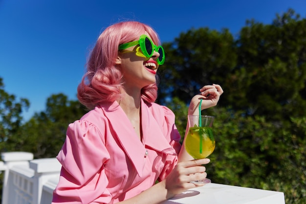 Fashionable woman in pink dress outdoors with cocktail Summer day