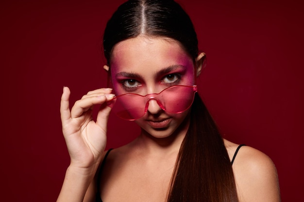 Fashionable woman pink glasses bright makeup posing black jersey pink background unaltered