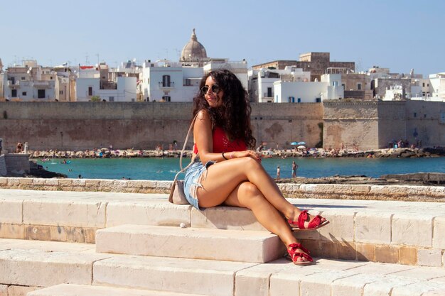 Photo fashionable woman sitting on retaining wall