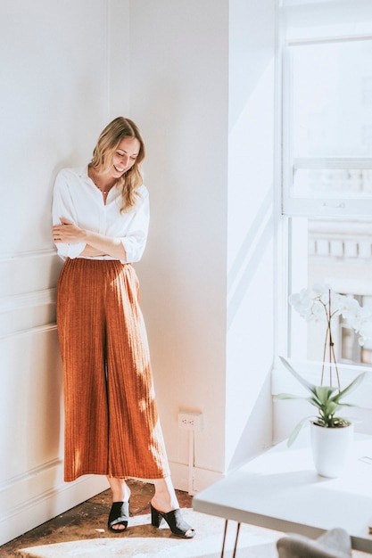 Photo fashionable woman standing by a white wall