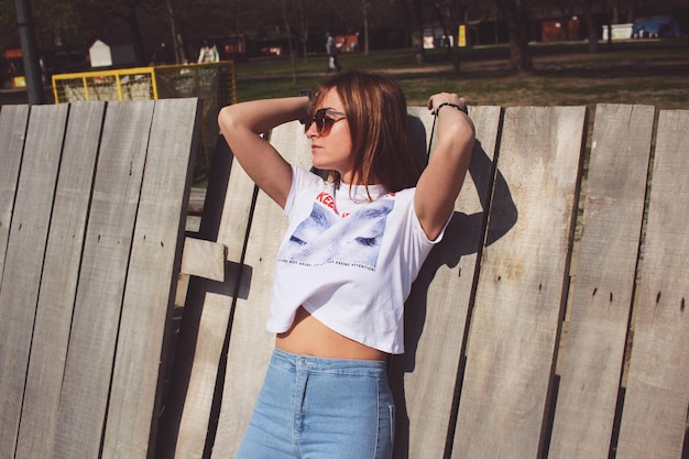 Photo fashionable woman standing by wooden fence