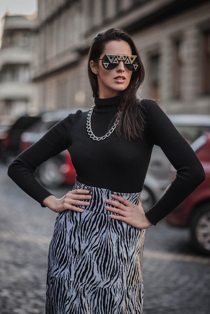 Photo fashionable woman standing on footpath in city