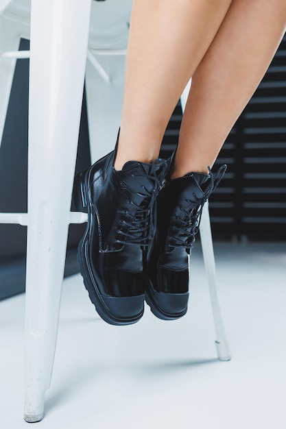 A fashionable woman stands in a store and measures autumn shoes Closeup of female legs in stylish fashion leather black laceup boots New seasonal collection of women's shoes