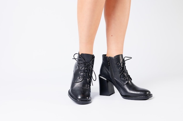 Fashionable woman in stylish leather shoes with heels Female beautiful legs with fashionable boots in the studio on an isolated white background