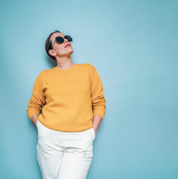 Fashionable woman in sunglasses Posing on a blue background lo